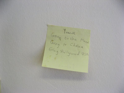 Close-up of “Must Go To! (2012)”: handwritten post-it note installation on wall, dimensions variable 